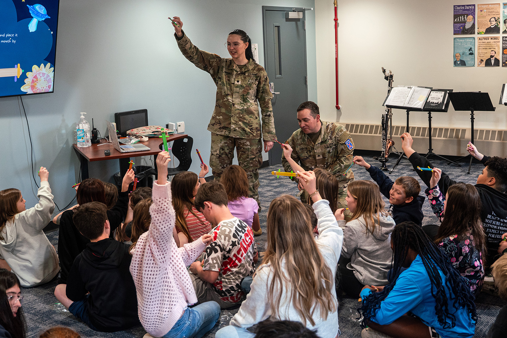 Soldiers in uniform instructing a group of young students