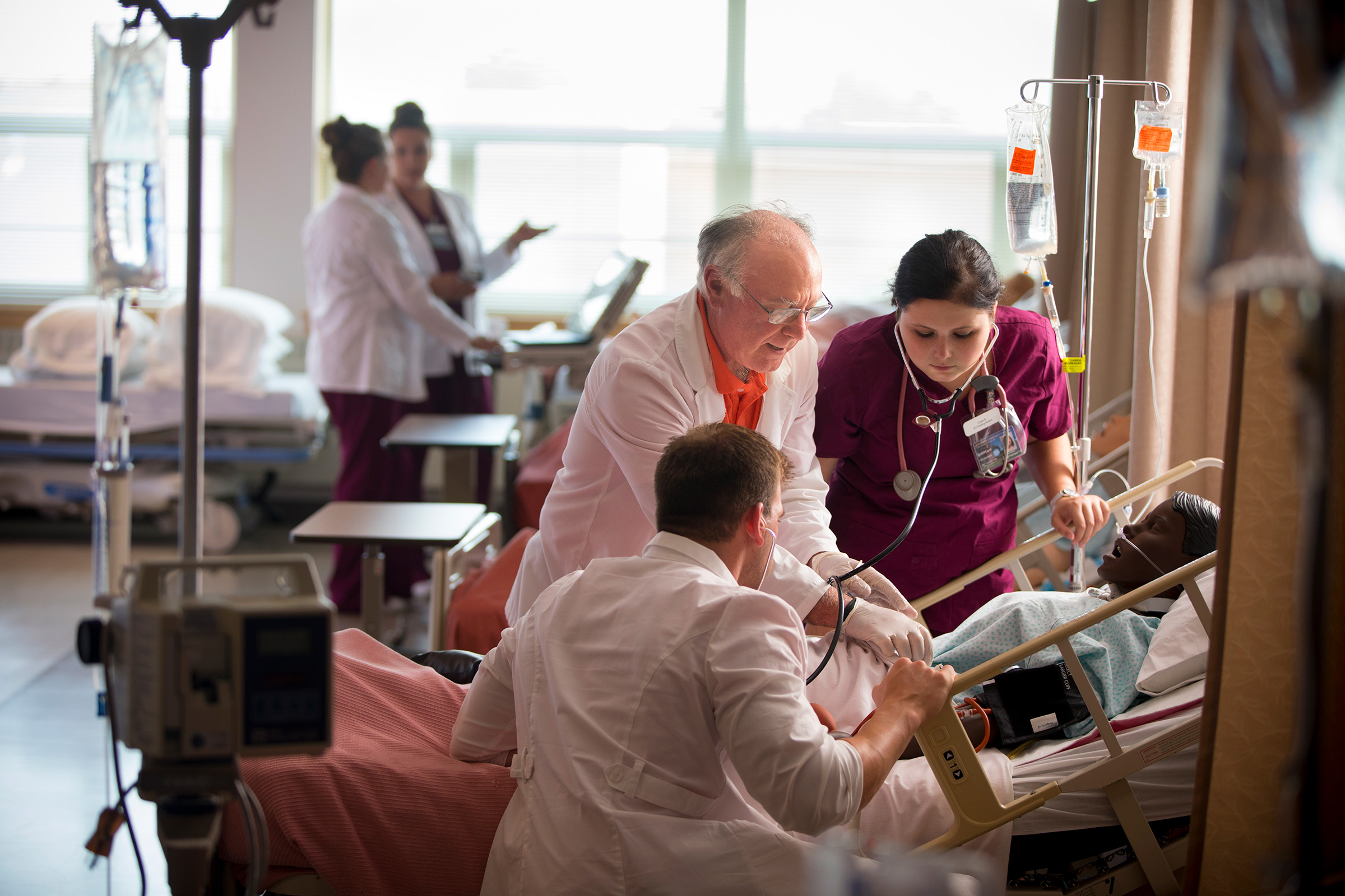 Instructor and nursing students inspecting dummy patient