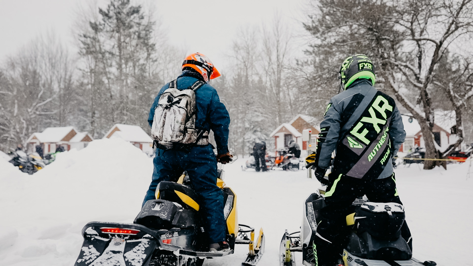 Back view of two people sitting on snowmobiles